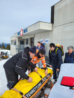 Rettungskräfte kümmern sich um eine verletzte Person in verschneiter Umgebung.