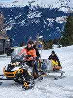 Rettungskräfte transportieren eine verletzte Person auf einem Schlitten im Schnee.