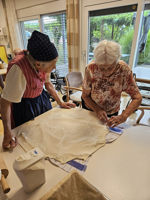 Zwei Frauen backen gemeinsam Teig in einer modernen Küche.