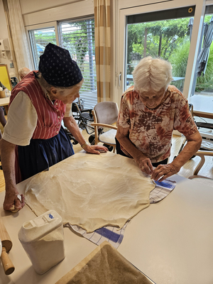 Zwei Frauen backen gemeinsam Teig in einer modernen Küche.