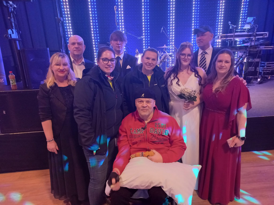 Eine Gruppe von Menschen posiert zusammen bei einer Feier, darunter eine Braut.
