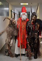 Der Nikolaus steht zwischen zwei Gestalten in traditionellen Kostümen.