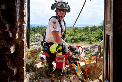 Ein Feuerwehrmann in Schutzkleidung sitzt auf Trümmern und bereitet sich vor.