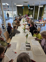 Gruppen von Menschen spielen Bingo in einem geselligen Raum mit Blumen.