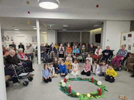 Eine Gruppe von Kindern und Senioren sitzt zusammen in einem festlichen Raum.
