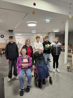 Eine Gruppe von sieben Menschen in einem Raum, darunter zwei ältere Frauen im Rollstuhl.