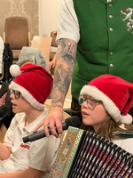 Zwei Kinder mit Weihnachtsmützen singen und halten Mikrofone in der Hand.