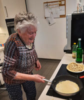 Eine ältere Frau brät einen Pfannkuchen in der Küche.