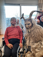 Zwei Personen in Rollstühlen, einer verkleidet als mystische Figur mit Hörnern.