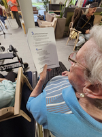 Eine ältere Person hält ein Blatt Papier mit Text in der Hand.