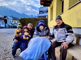 Eine Familie mit zwei Kindern und einem älteren Mann auf einer Bank im Freien.