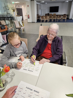 Ein bild zeigt ein Kind und eine ältere Frau beim Bingo-Spiel.