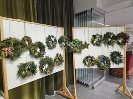 Zwei Ständer mit dekorierten Weihnachtskränzen in verschiedenen Grün- und Farbtönen.