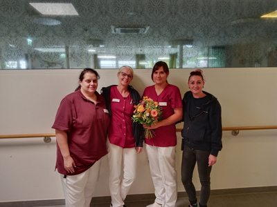 Vier Frauen in Uniformen stehen zusammen und halten einen Blumenstrauß.