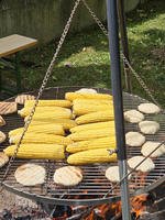 Gegrillter Mais und Brot auf einem Rost über offenem Feuer.