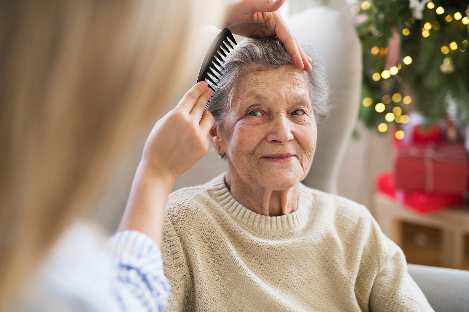 Einer älteren Frau werden liebevoll die Haare gekämmt.