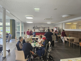 Personen essen und unterhalten sich in einem hellen Speisesaal.
