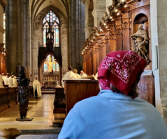 Eine Person sitzt in einer Kirche und blickt auf einen Altar.