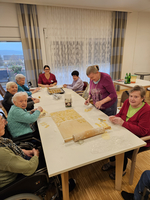 Senioren backen gemeinsam Plätzchen an einem Tisch.