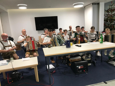 Eine Gruppe von Musikern spielt gemeinsam auf Akkordeons in einem festlichen Raum.