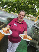 Eine Frau mit Brille hält zwei Teller mit Hähnchen und Brot.
