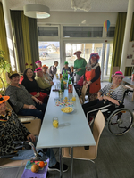 Gruppe von Menschen feiert mit Hüten und Getränken in einem hellen Raum.