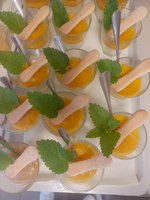 Gläser mit gelbem Dessert, dekoriert mit Minzblättern und Biskuitsticks.
