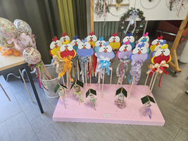 Bunte Hühnerfiguren aus Pappe mit Schleifen auf langen Stäben.