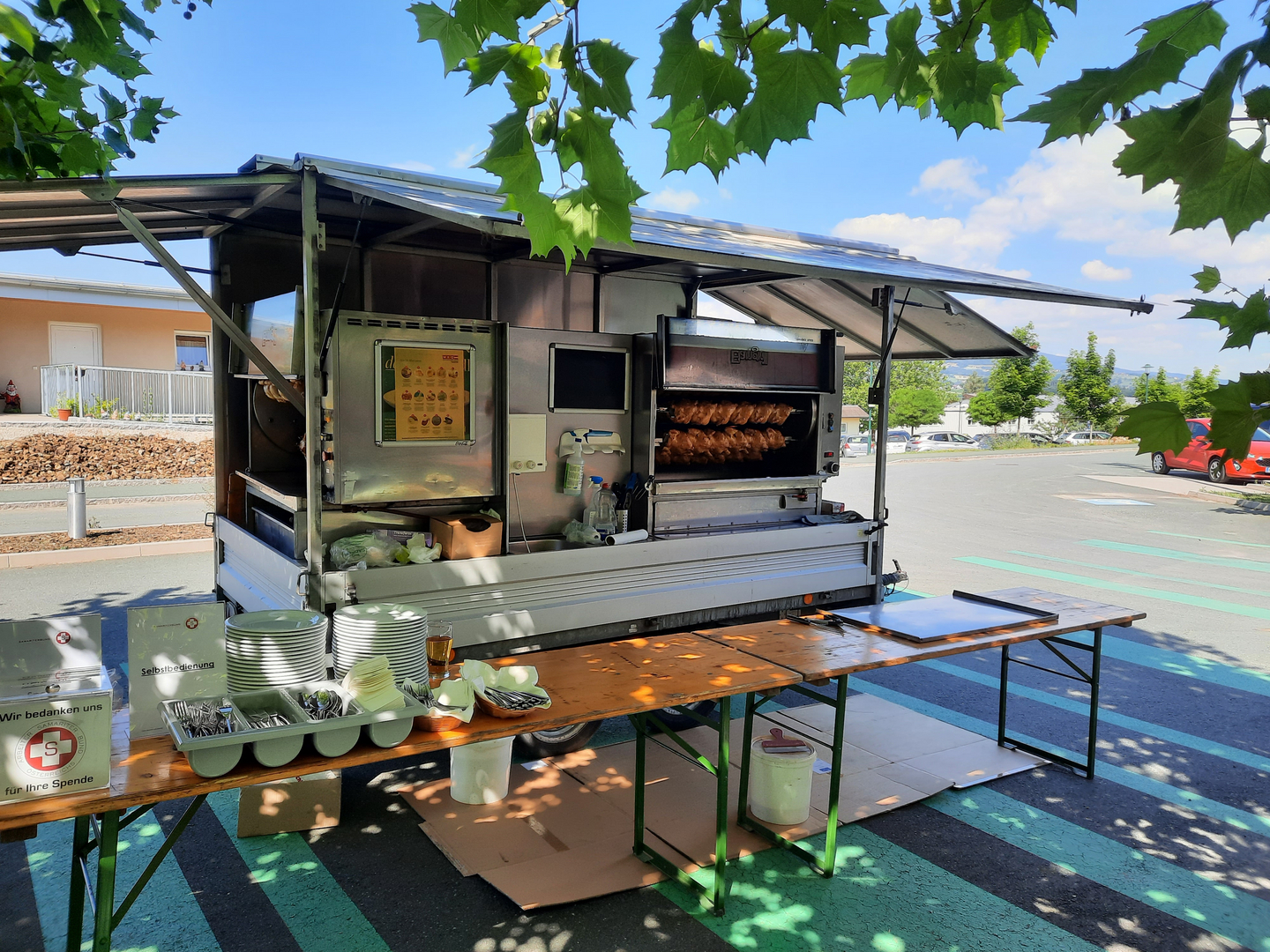 Ein Verkaufsstand mit gegrilltem Hähnchen und Geschirr auf einem Tisch.